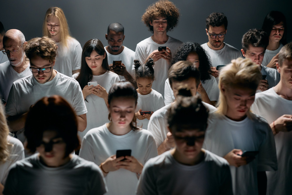 Eine Gruppe Menschen in weißen T-Shirts, die alle auf ihr Smartphone blicken.